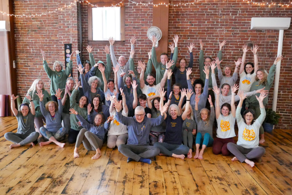 Image of a variety of yoga teachers with their hands raised.